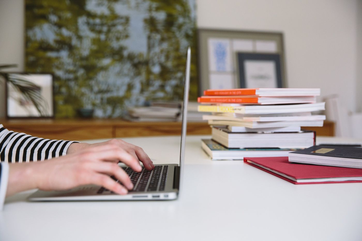 Hands typing on a laptop beside a stack of law books